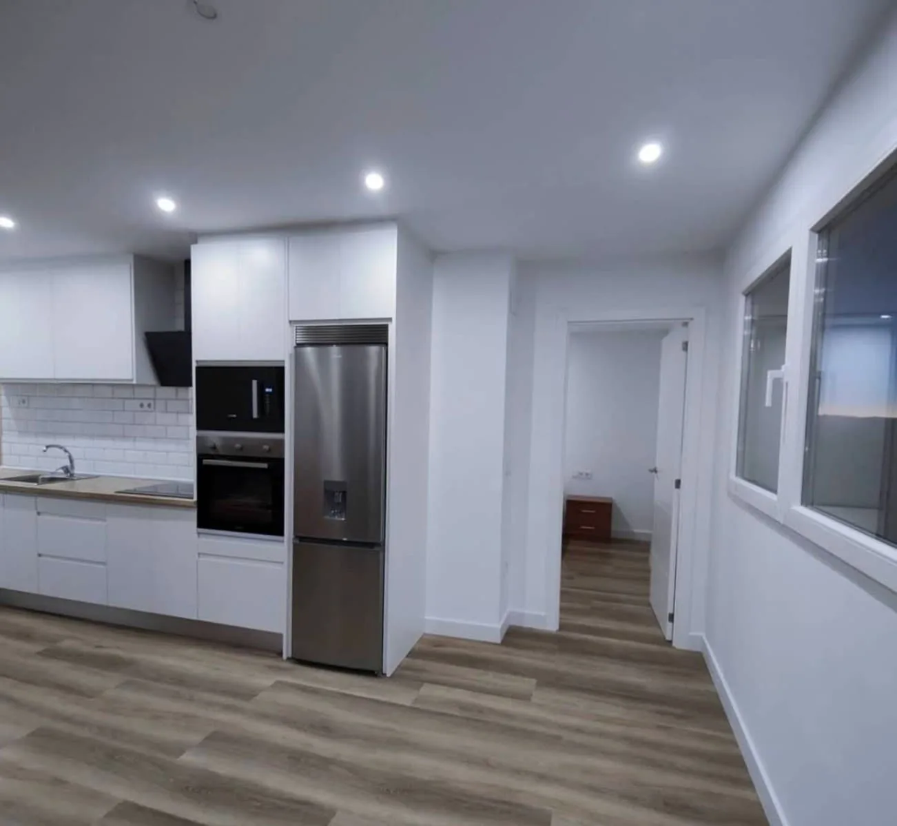 Cocina con mobiliario blanco y suelo de tarima