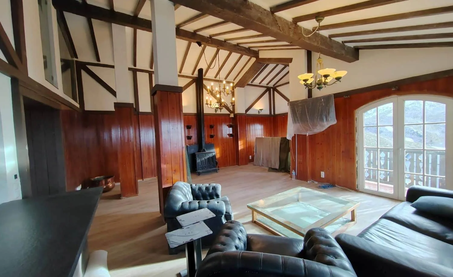 Salón rústico con revestimiento de madera y vigas vistas