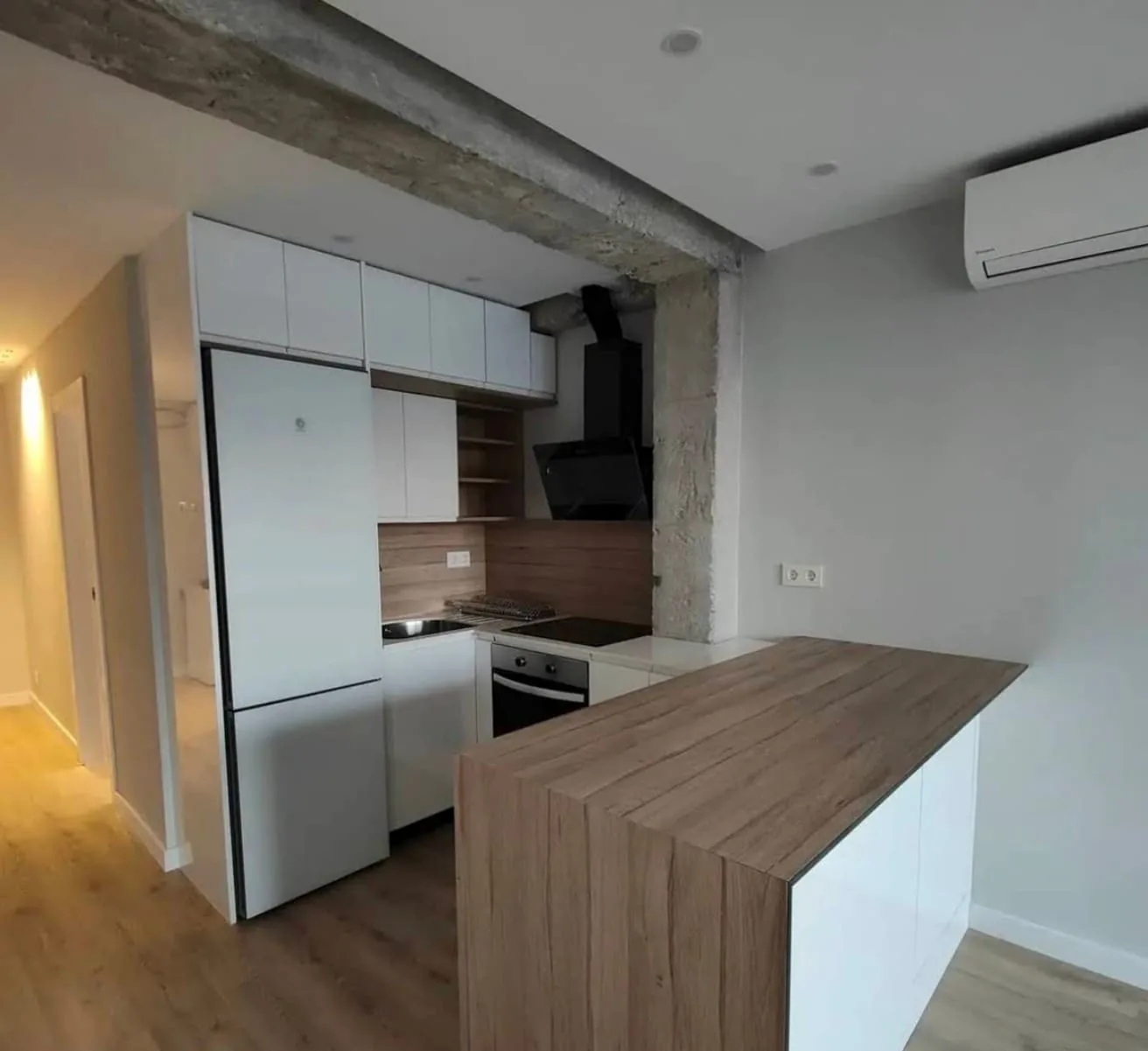 Cocina con península de madera y viga vista
