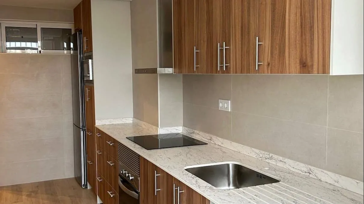 Cocina con muebles de madera y encimera efecto mármol