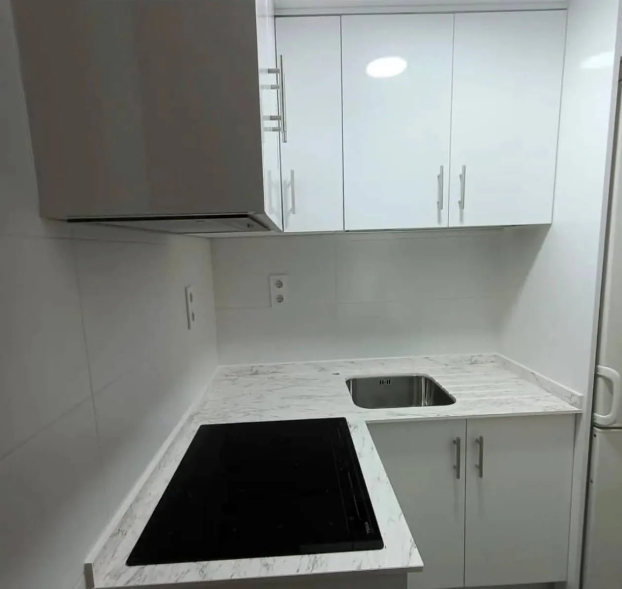 Cocina en L con encimera efecto mármol y muebles blancos