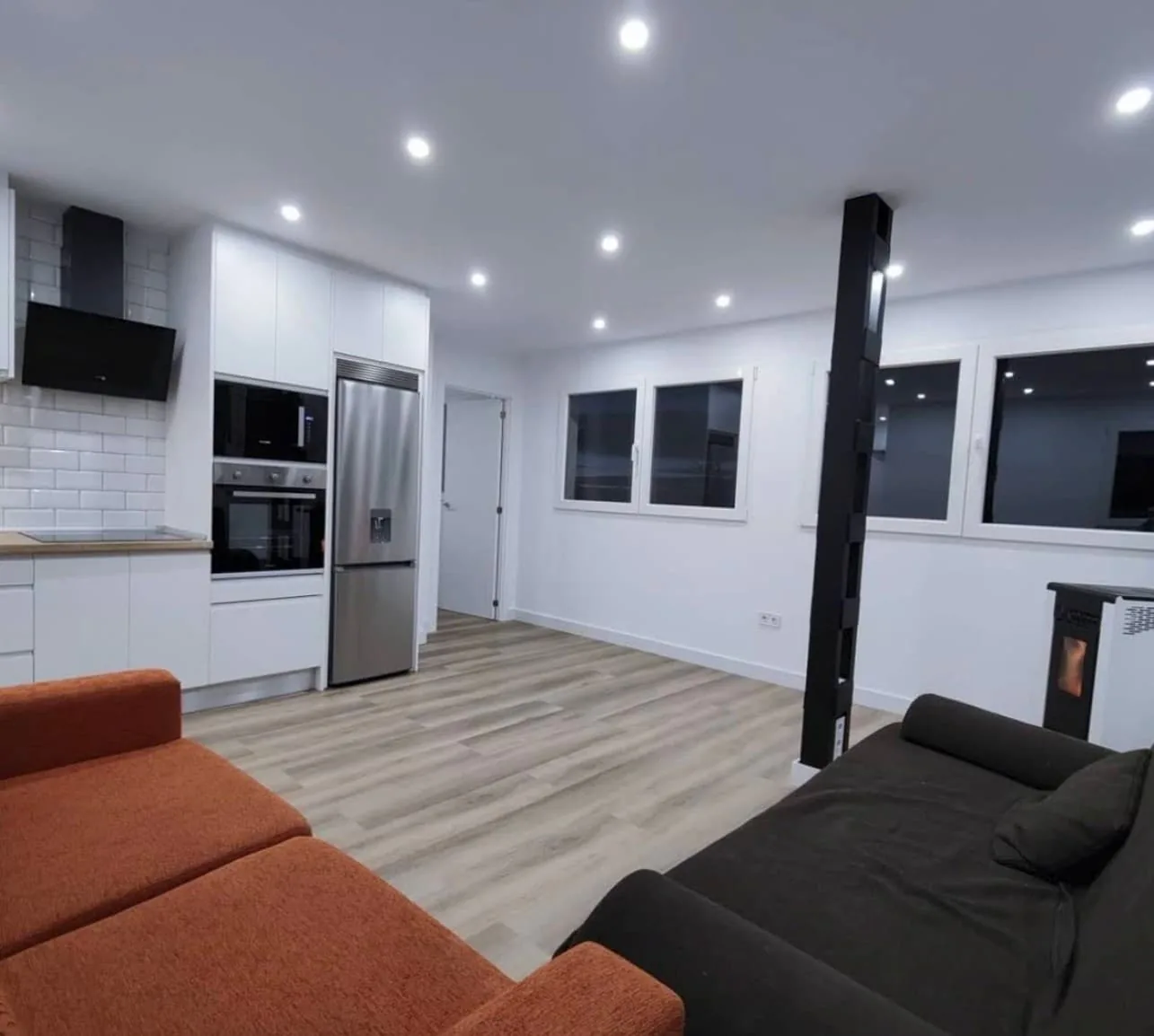 Salón con cocina abierta, sofás y estufa