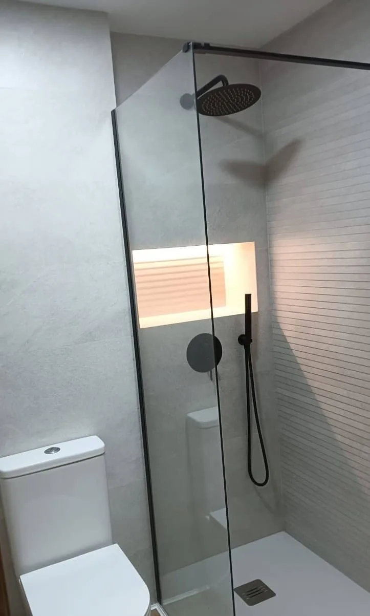 Ducha con mampara, grifería negra y hornacina iluminada