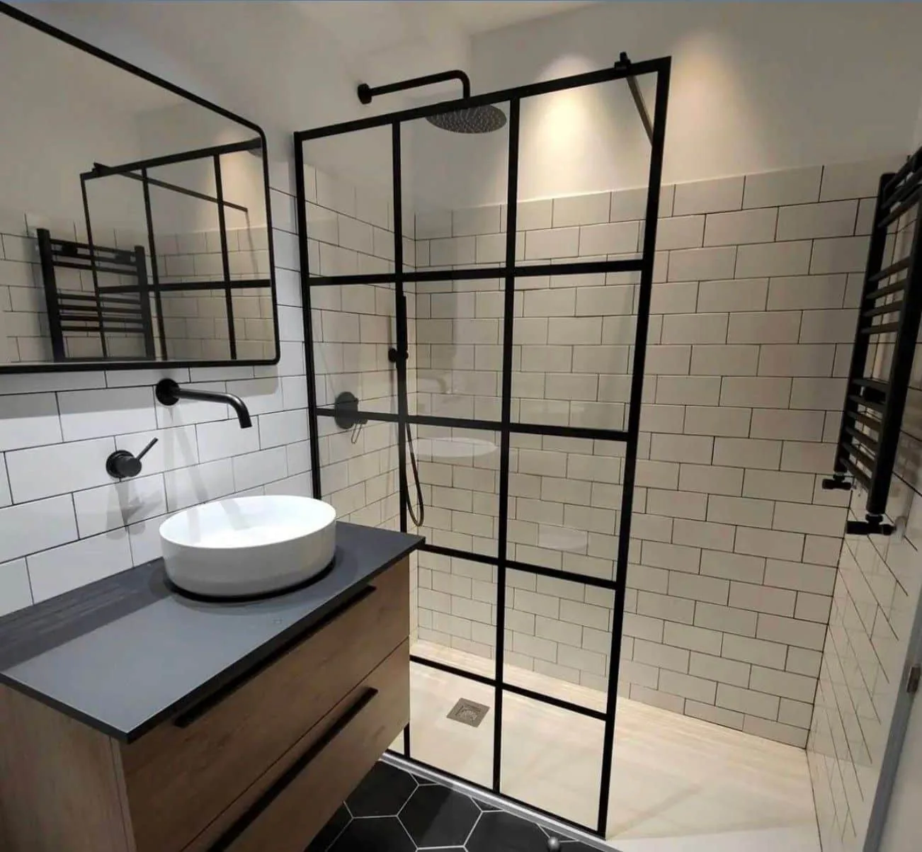 Baño con mampara de perfilería negra y lavabo sobre mueble de madera