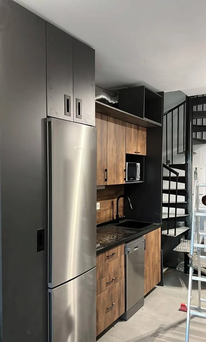 Cocina con muebles de madera y negro junto a frigorífico